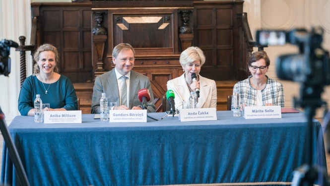 Preses konferencē pie galda ar zilu galdautu sēž izglītības un zinātnes ministre Anda Čakša, LU rektors Gundars Bērziņš, LU Izglītības zinātņu un psiholoģijas fakultātes (IZPF) studiju prodekāne profesore Anika Miltuze un LU Izglītības inovāciju nodaļas vadītāja Mārīte Seile