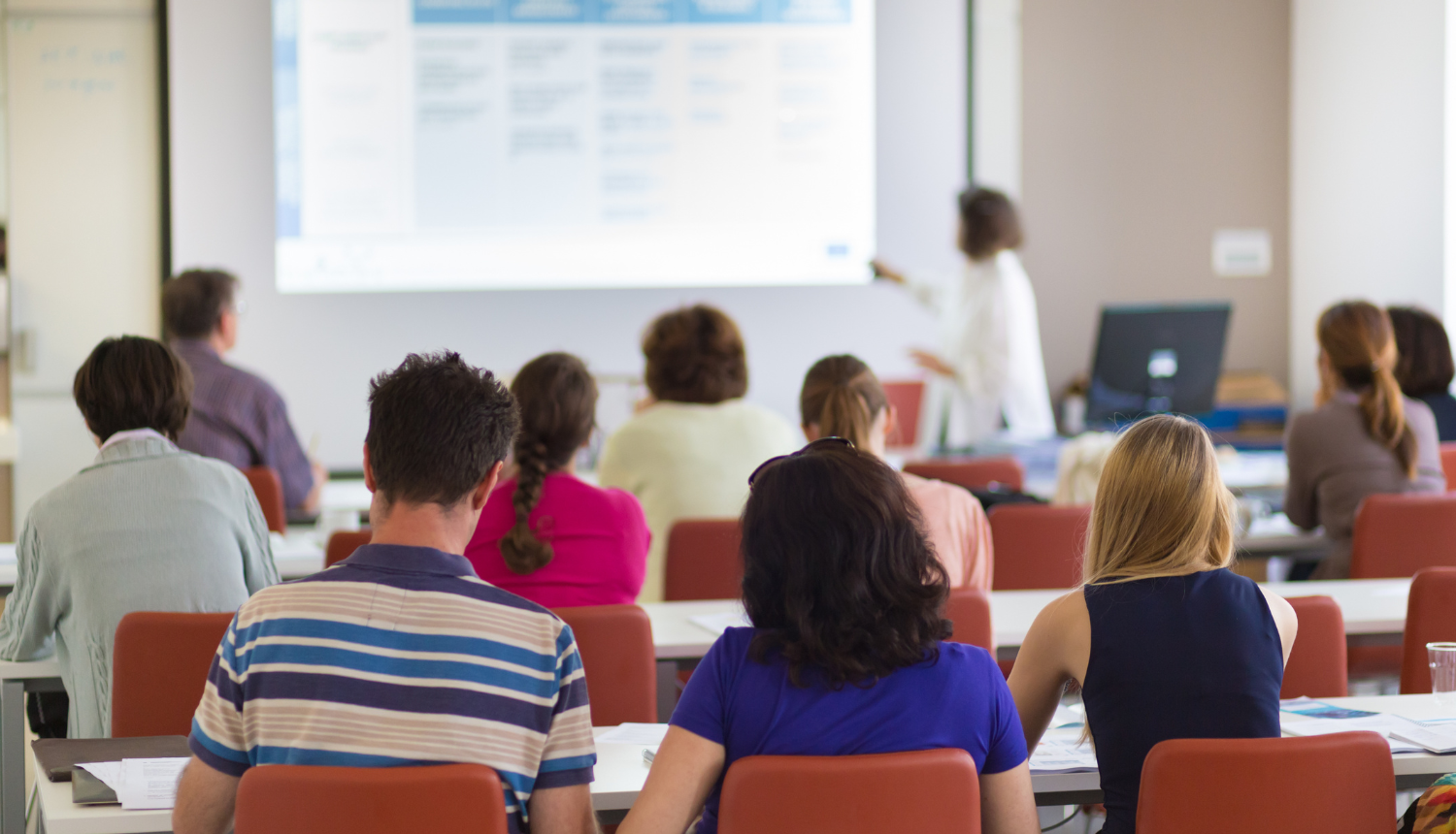 Studenti mācas auditorijā, lektors rāda prezentāciju.