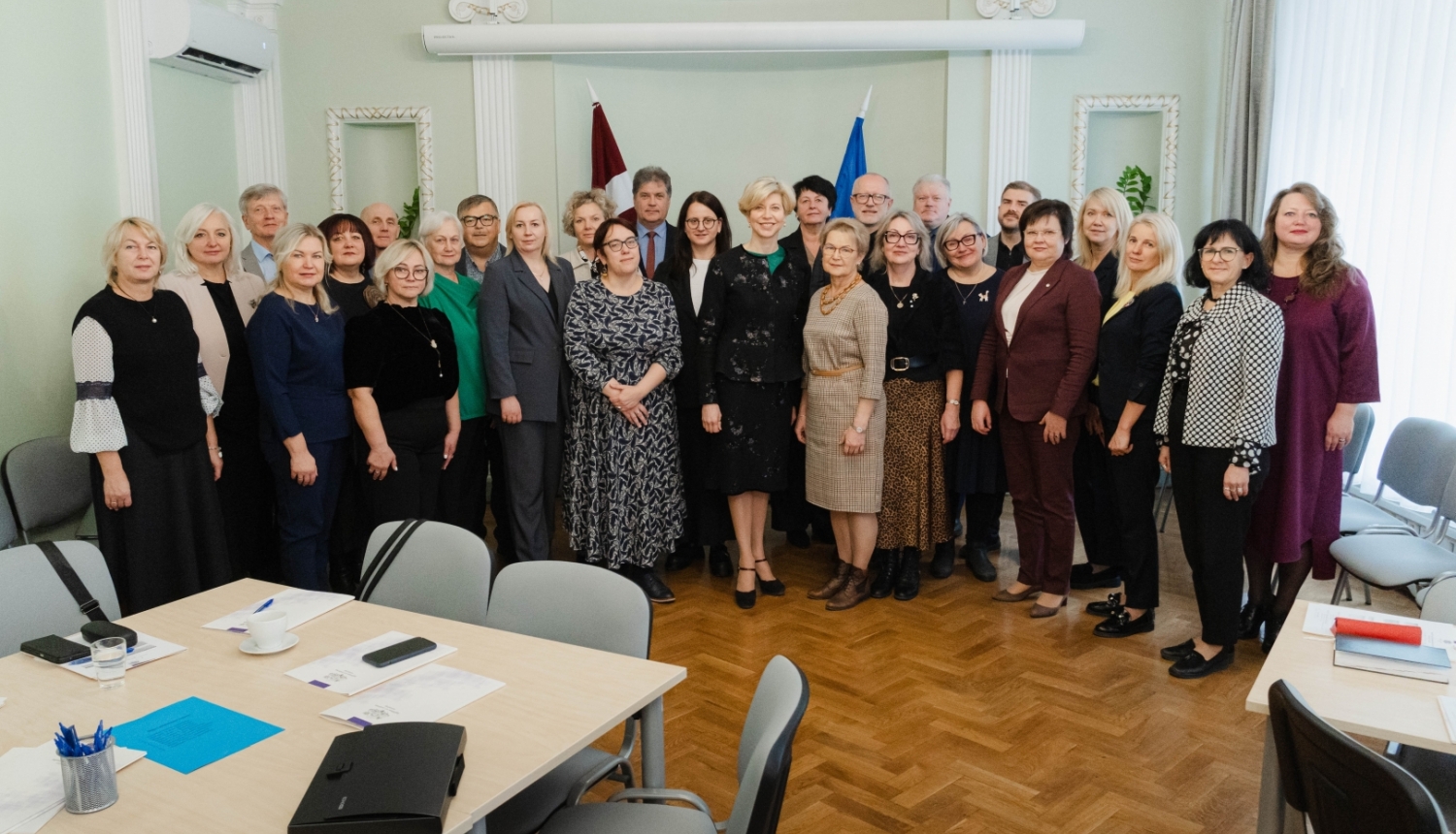 Ministres un skolu direktoru kopbilde pie Latvijas un ES karogiem.