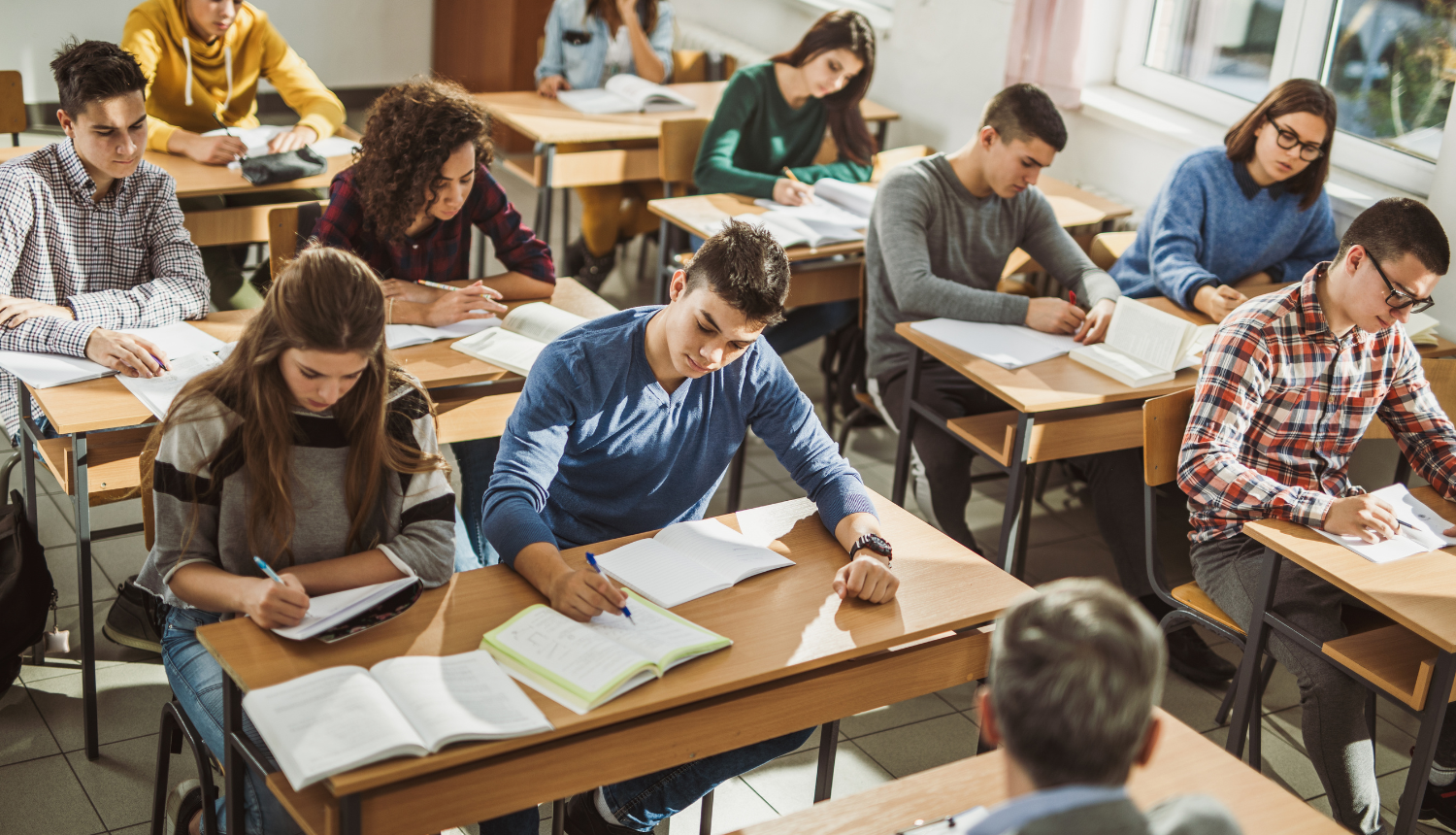 Jaunieši sēž klasē un mācās, priekšā sēž skolotājs