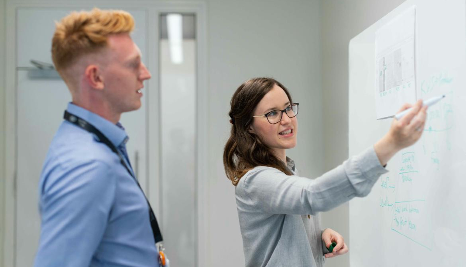 A woman writes on a blackboard, explains information to a man. The image is for illustrative purposes only..