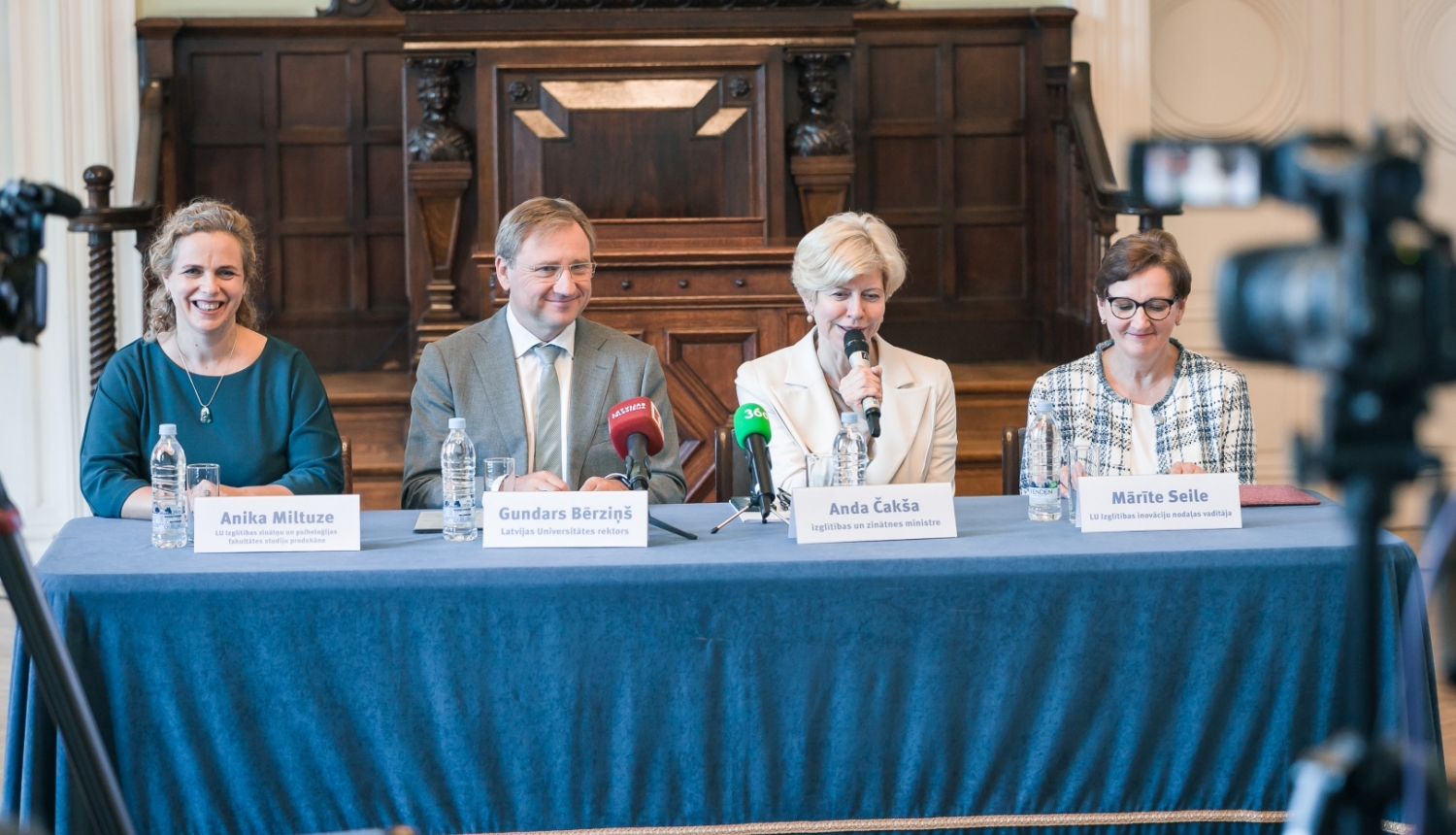 Preses konferencē pie galda ar zilu galdautu sēž izglītības un zinātnes ministre Anda Čakša, LU rektors Gundars Bērziņš, LU Izglītības zinātņu un psiholoģijas fakultātes (IZPF) studiju prodekāne profesore Anika Miltuze un LU Izglītības inovāciju nodaļas vadītāja Mārīte Seile